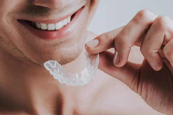 A man holding a mouth guard and smiling