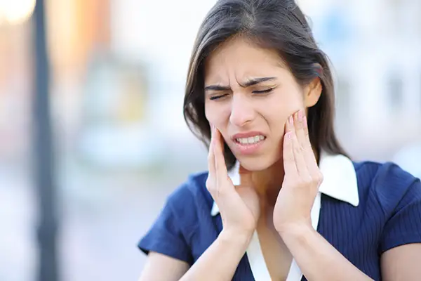 A woman grasping her jaw with both hands in pain at Osborne Dentistry in Lebanon, OR