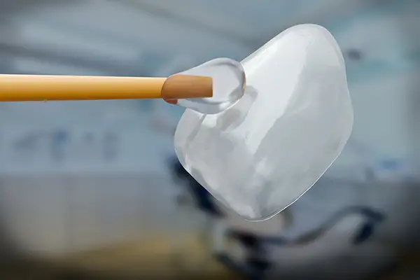 A close-up of a dental veneer being delicately touched with a tool A close-up of a dental veneer being delicately touched with a tool