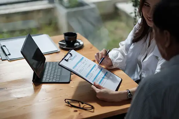 Two people reviewing financial and insurance paperwork